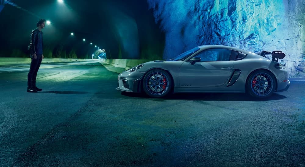 A silver 2025 Porsche 718 Cayman GT4 RS is shown parked in a large tunnel near a person.