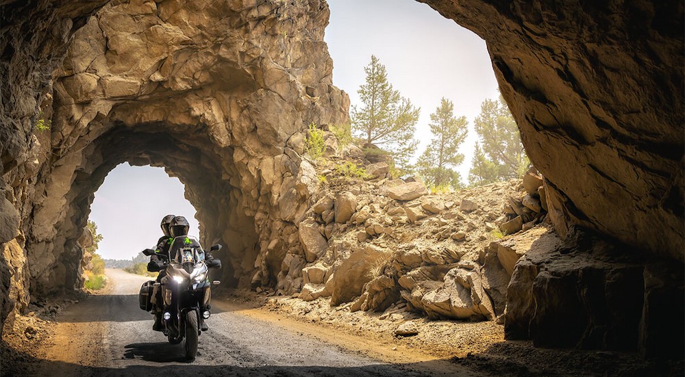 A black and green 2025 Kawasaki Versys 1100 is shown driving through a tunnel.