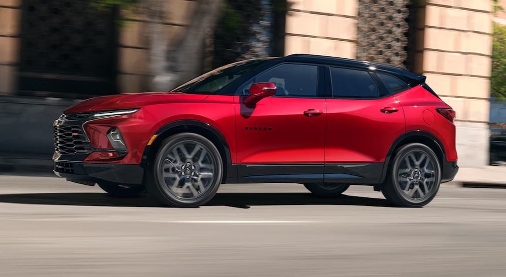 A red 2025 Chevy Blazer RS is shown driving on a city street.