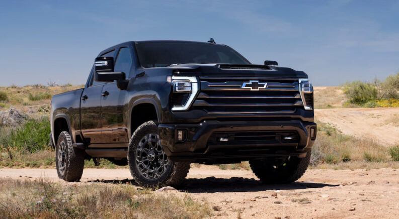 A black 2024 Chevy Silverado 2500 HD High Country parked off-road and angled right.