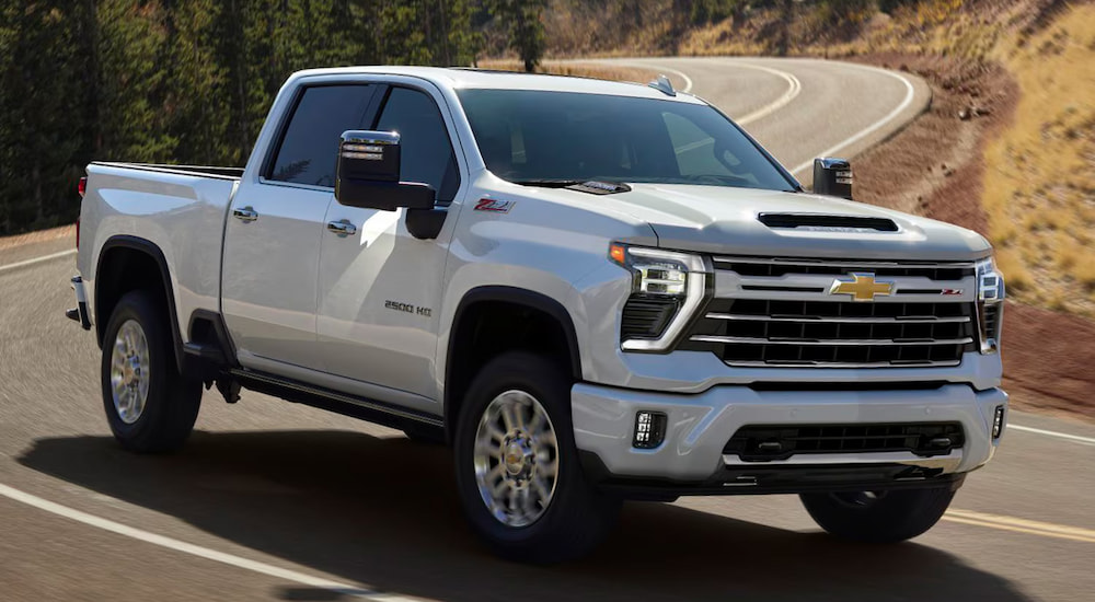 A white 2024 Chevy Silverado 2500 HD driving around a bend.