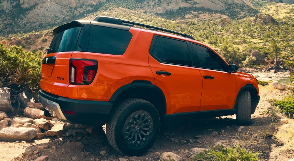 An orange 2026 Honda Passport Trailsport is shown from the side.