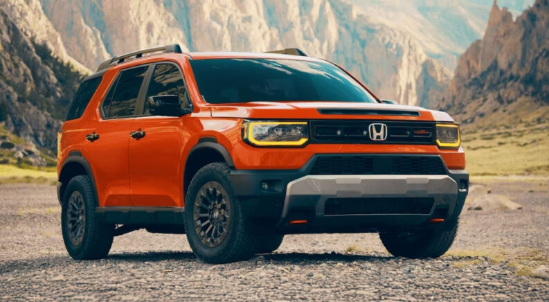 An orange 2026 Honda Passport Trailsport is shown from the front at an angle after leaving a Honda dealer near Monroe.