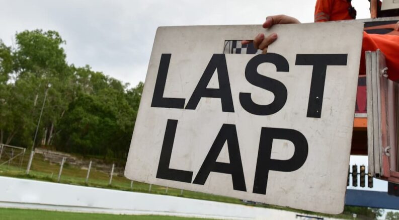 A person is shown holding a last lap sign.