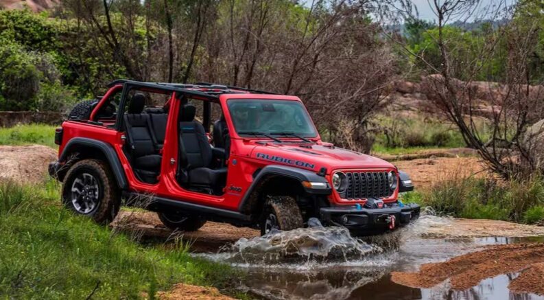 A red 2025 Jeep Wrangler Rubicon is shown driving off-road.