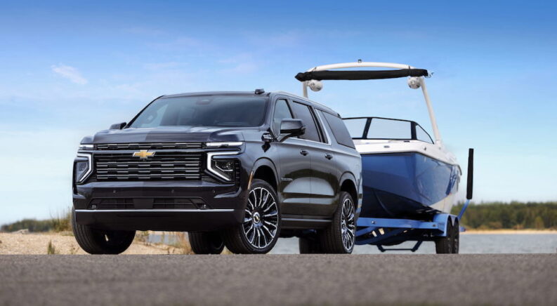 A black 2025 Chevy Suburban High Country is shown from the front at an angle after leaving a Chevy dealer near Chelsea.