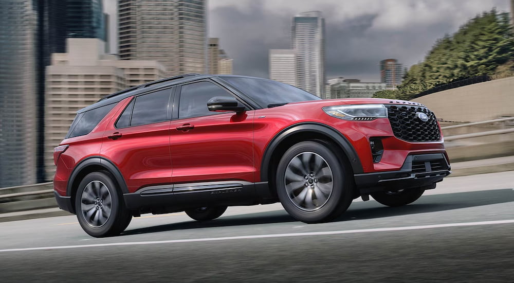 A red 2025 Ford Explorer ST-Line driving through a city from a dealer with a Ford Explorer for sale.