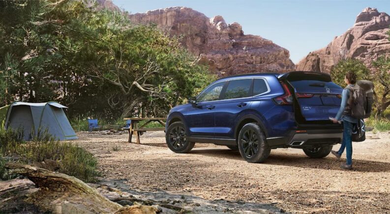 A blue 2025 Honda CR-V Sport Touring Hybrid is parked at a campsite.