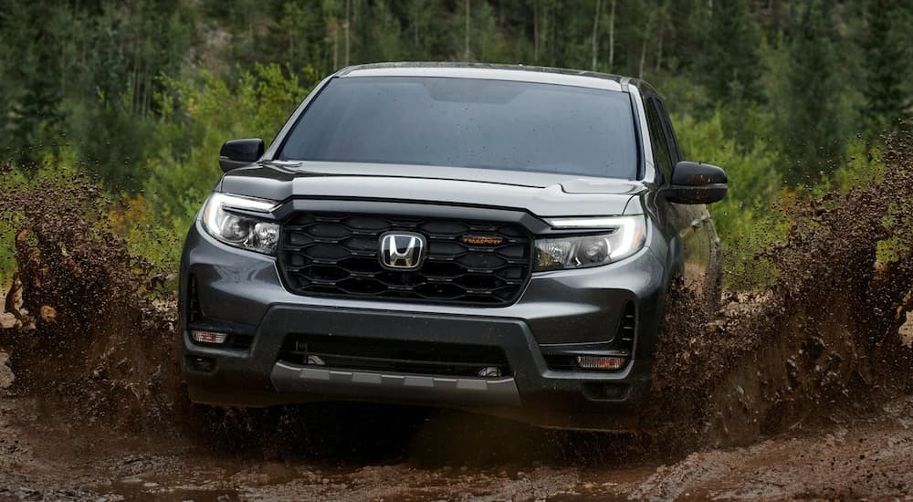 A silver 2025 Honda RIdgeline Trailsport is off-roading through a muddy path.