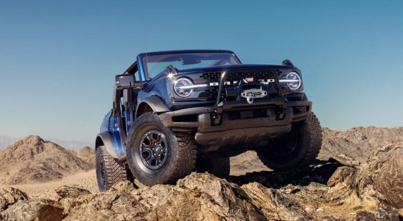 A blue 2021 Ford Bronco parked off-road on rocky terrain.