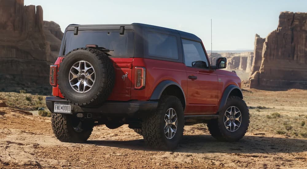 Rear view of a red 2021 Ford Bronco parked off-road after visiting a dealer with a used Ford Bronco for sale.