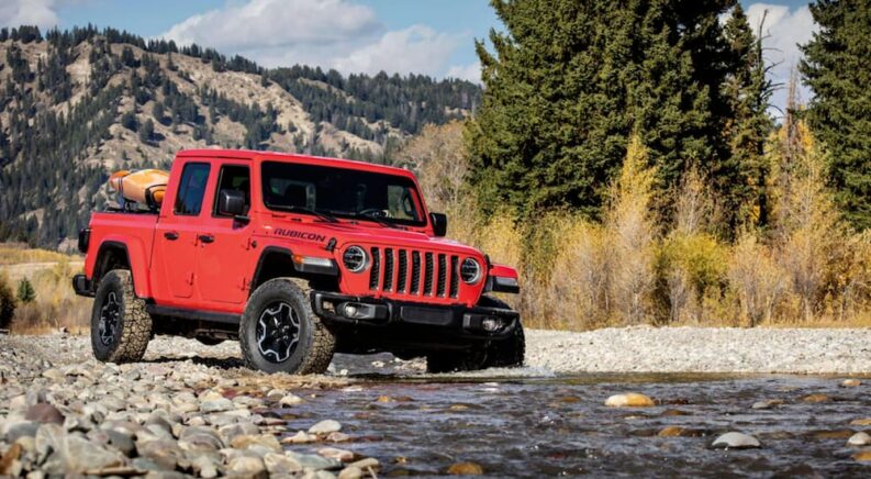 A red 2020 Jeep Gladiator Rubicon driving through a stream.