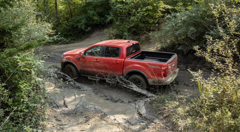 A red 2021 Ford Ranger Tremor Lariat is driving through mud.