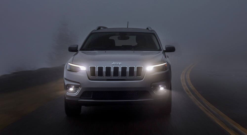 A silver 2020 Jeep Cherokee driving through fog.