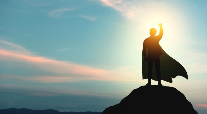 A man with a superhero cape on top of a mountain