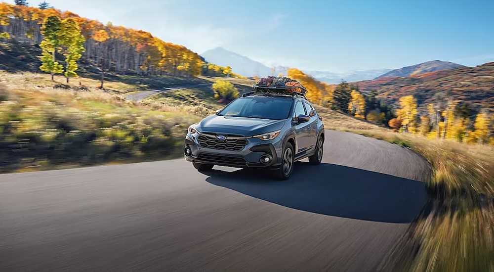 A blue 2023 Subaru Crosstrek driving on a sunny day.