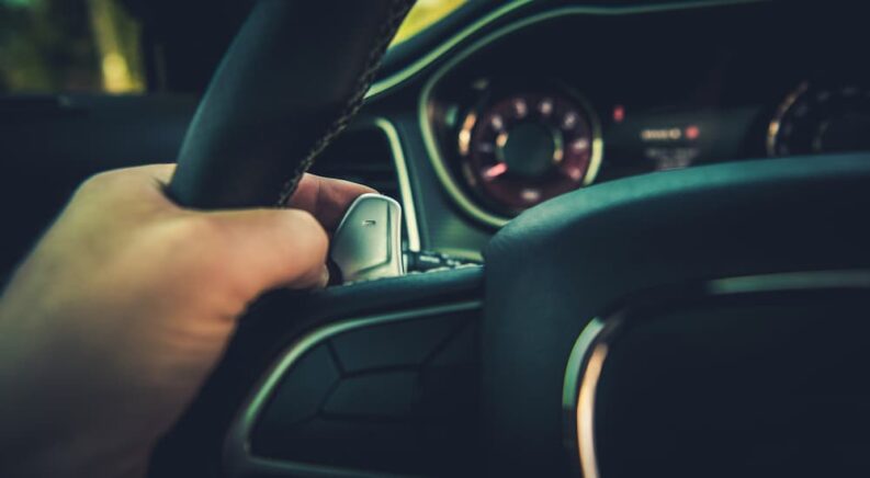 A hand using the paddle shifter on a vehicle