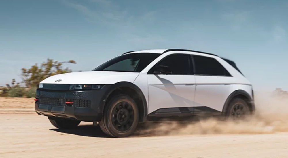 White 2025 Hyundai IONIQ 5 kicking up dirt as it drives off-road.