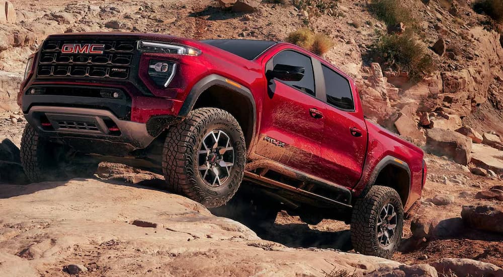 A red 2026 GMC Canyon AT4X off-roading on rocks