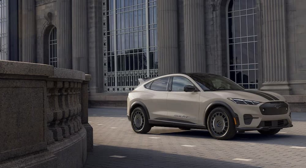 A tan 2025 Ford Mustang Mach-E parked near a stone building.