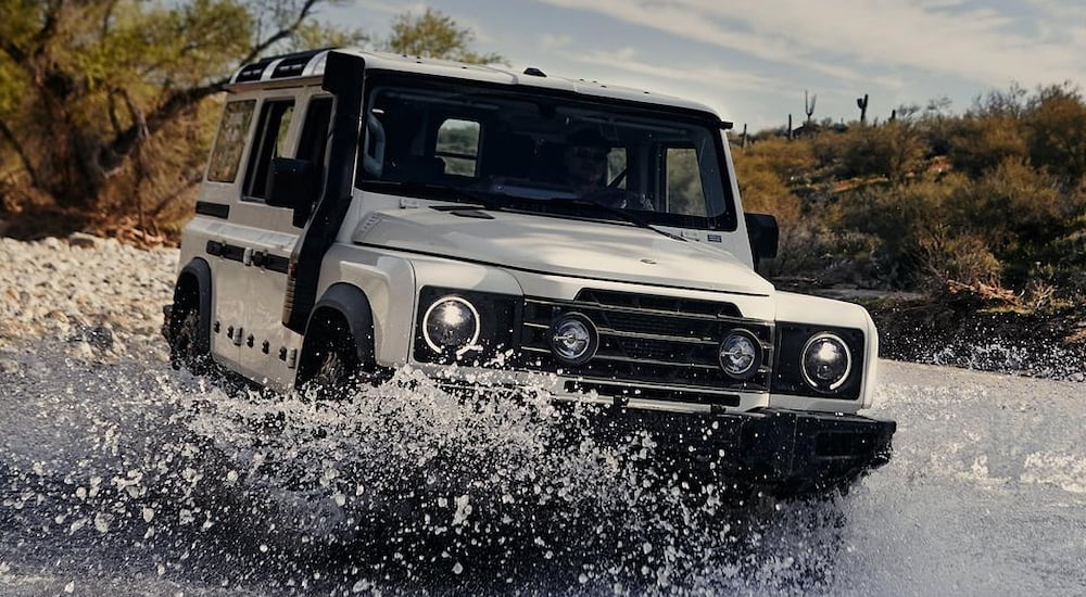 White 2025 INEOS Grenadier driving through a shallow river.