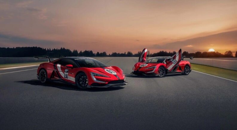 Two red YANGWANG U9 Xtreme hypercars parked on a racetrack at sunrise
