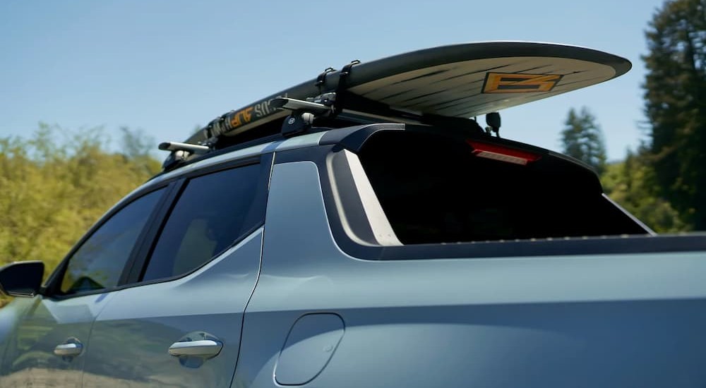 A surfboard on the roof of a blue 2026 Hyundai Santa Cruz.
