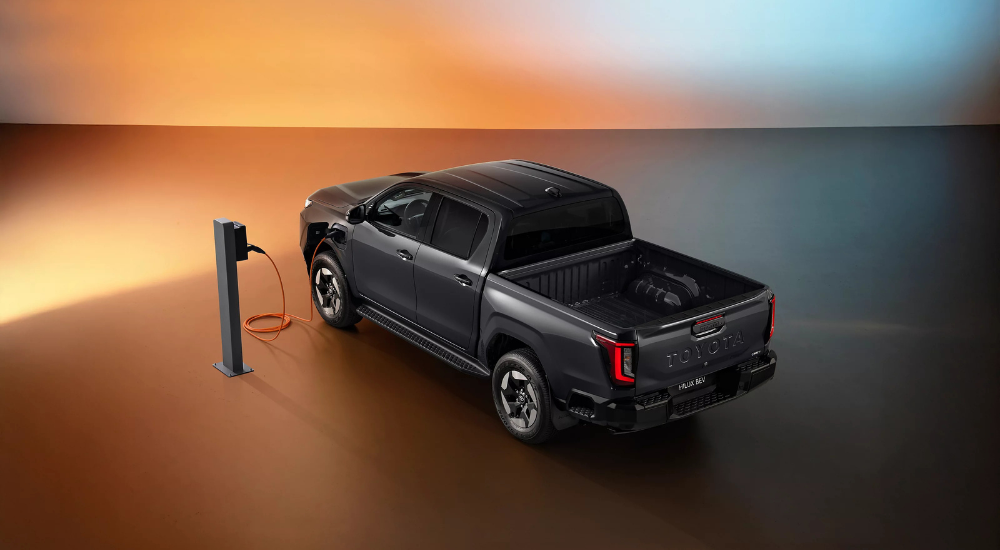 Grey 2026 Toyota Hilux BEV charging from the rear