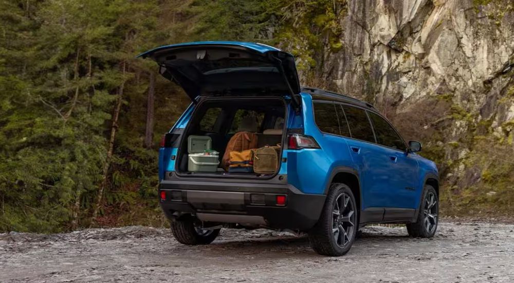 A rear view of a blue 2026 Jeep Cherokee with rear gate open.