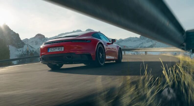 A red 2024 Porsche 911 Carrera GTS shown driving from rear.