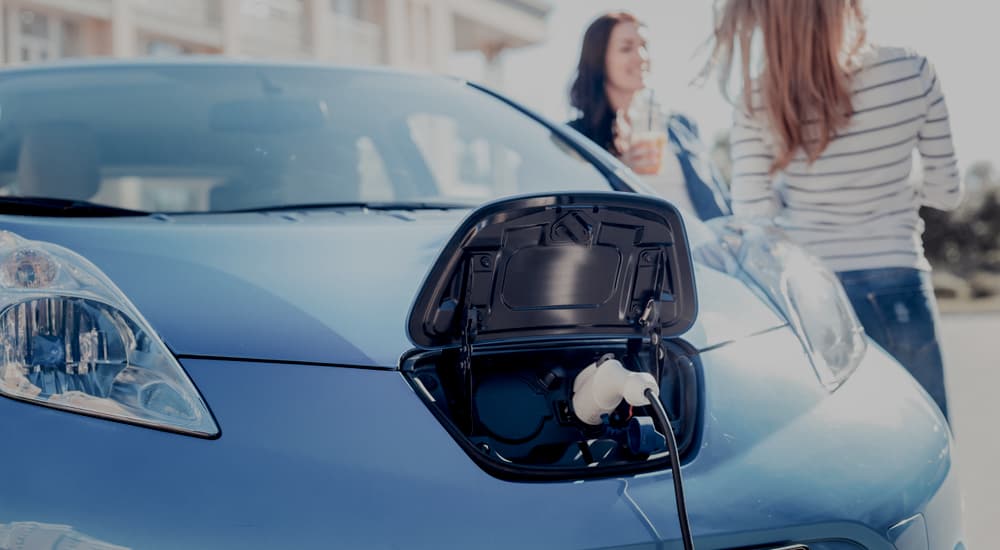 A blue EV parked into a charger.