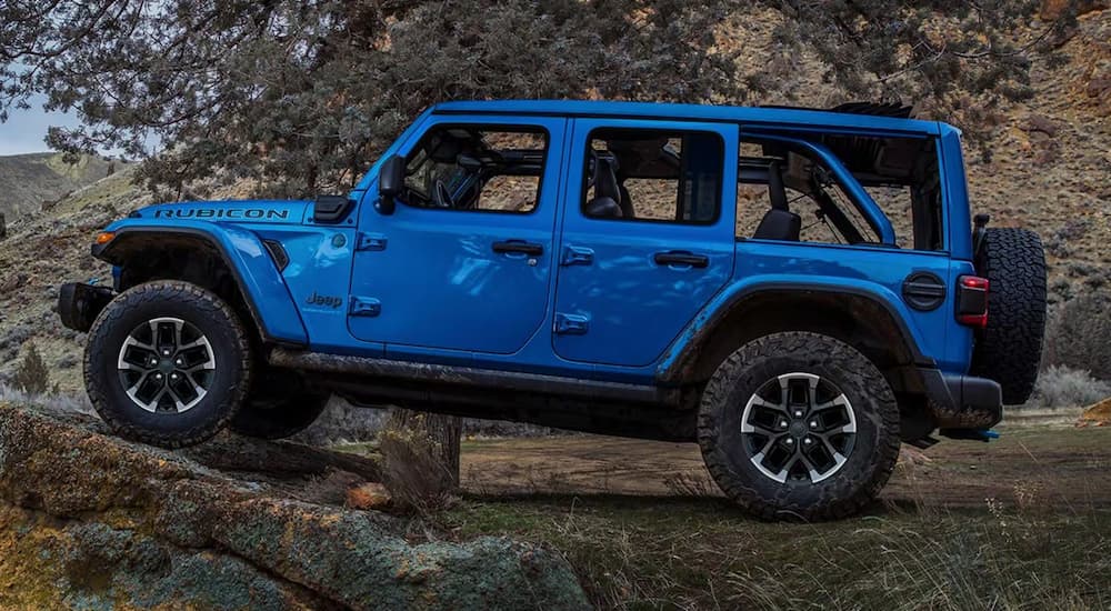 A blue 2025 Jeep Wrangler Rubicon parked off-road on a rock