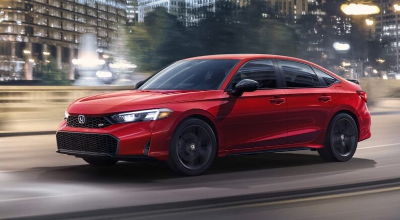 A red 2026 Honda Civic SI driving in a city.