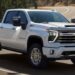 A white 2025 Chevy Silverado 2500 Z71 is shown driving on a highway.