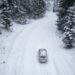 An aerial view of an SUV driving on a snowy road.