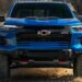 A blue 2024 Chevy Silverado 1500 ZR2 is shown driving off-road after visiting a Chevy dealer.