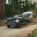 A green 2025 Chevy Tahoe Z71 is shown from the front while towing a trailer.