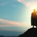 A man with a superhero cape on top of a mountain