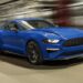 A blue 2022 Ford Mustang EcoBoost driving to a Ford dealer.