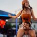 A woman on the shoulders of a man at an outdoor concert.