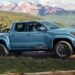 A blue 2026 Toyota Tacoma TRD Sport driving a trail.